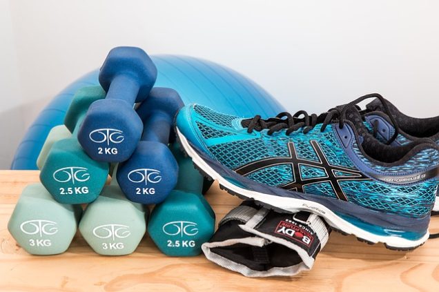 Apartments in San Antonio near Six Flags Fiesta A pair of Asics shoes and a pair of dumbbells are displayed on a wooden table, suggesting the presence of fitness equipment in an apartment's amenities.